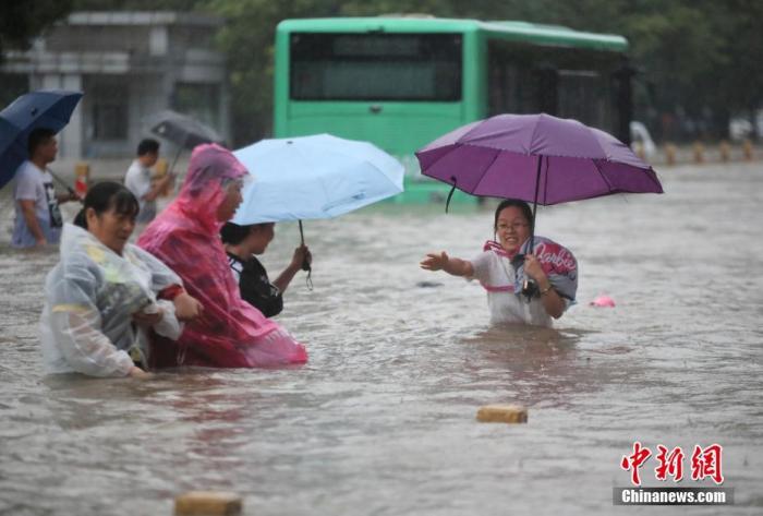 7月20日，鄭州遭遇強降雨，在經三路、農業路上，市民互相幫助走在齊腰深的積水里。 圖片來源：視覺中國